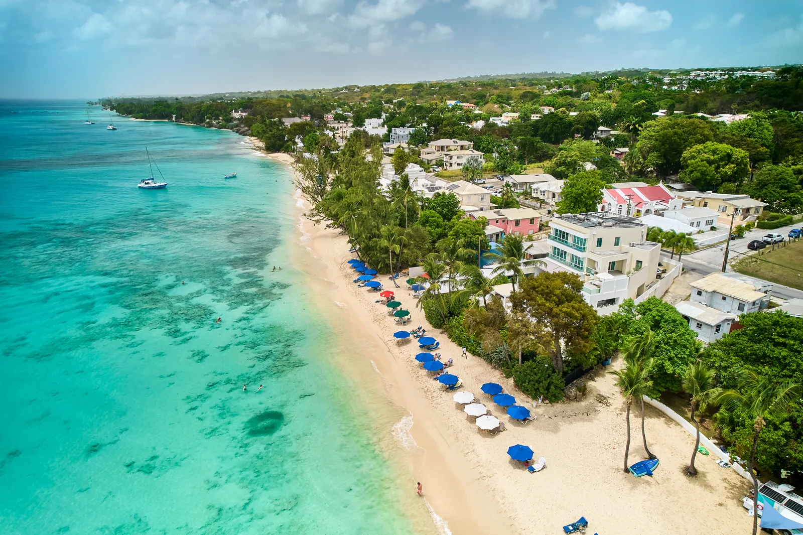 Turquoise coastal waters, a sandy beach and waterfront homes viewed from above